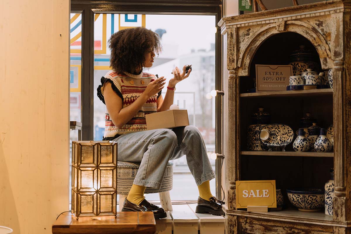Woman perched in storefront window. A CRM can help you provide a better shopping experience for would-be customers.